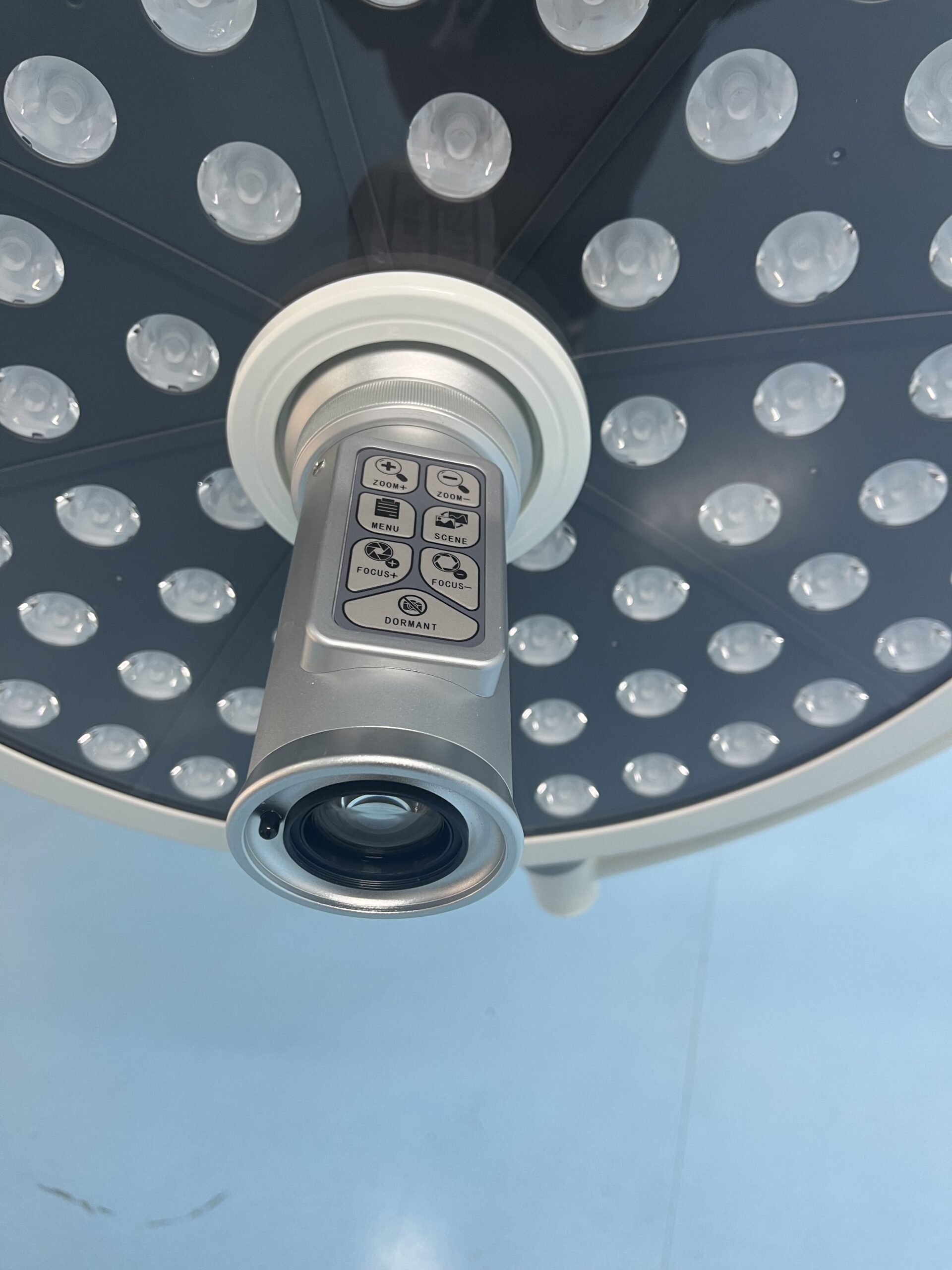 Ceiling-mounted surgical light system with integrated camera sharing ceiling space