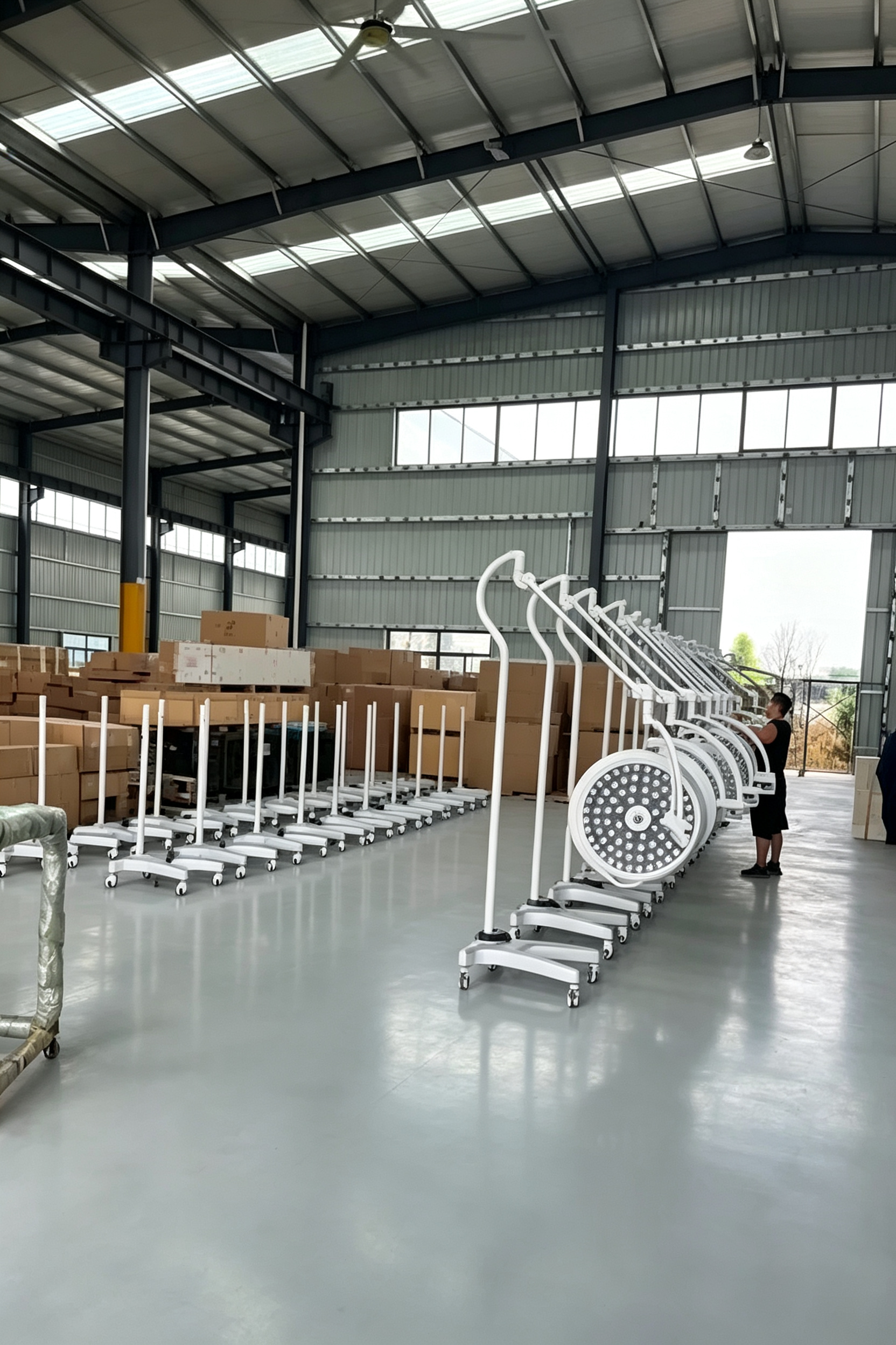 Technician performing quality inspection on ceiling surgical light assemblies in the factory test bay